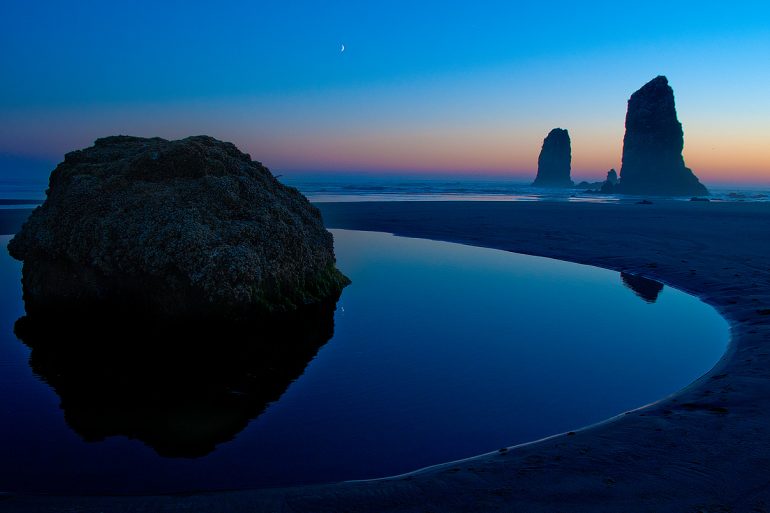 Photo of sea stacks and sunset reflected in tide pool at Canon Beach.