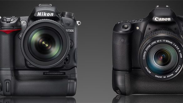 A Nikon D7000 and a Canon 60D, each with battery grip