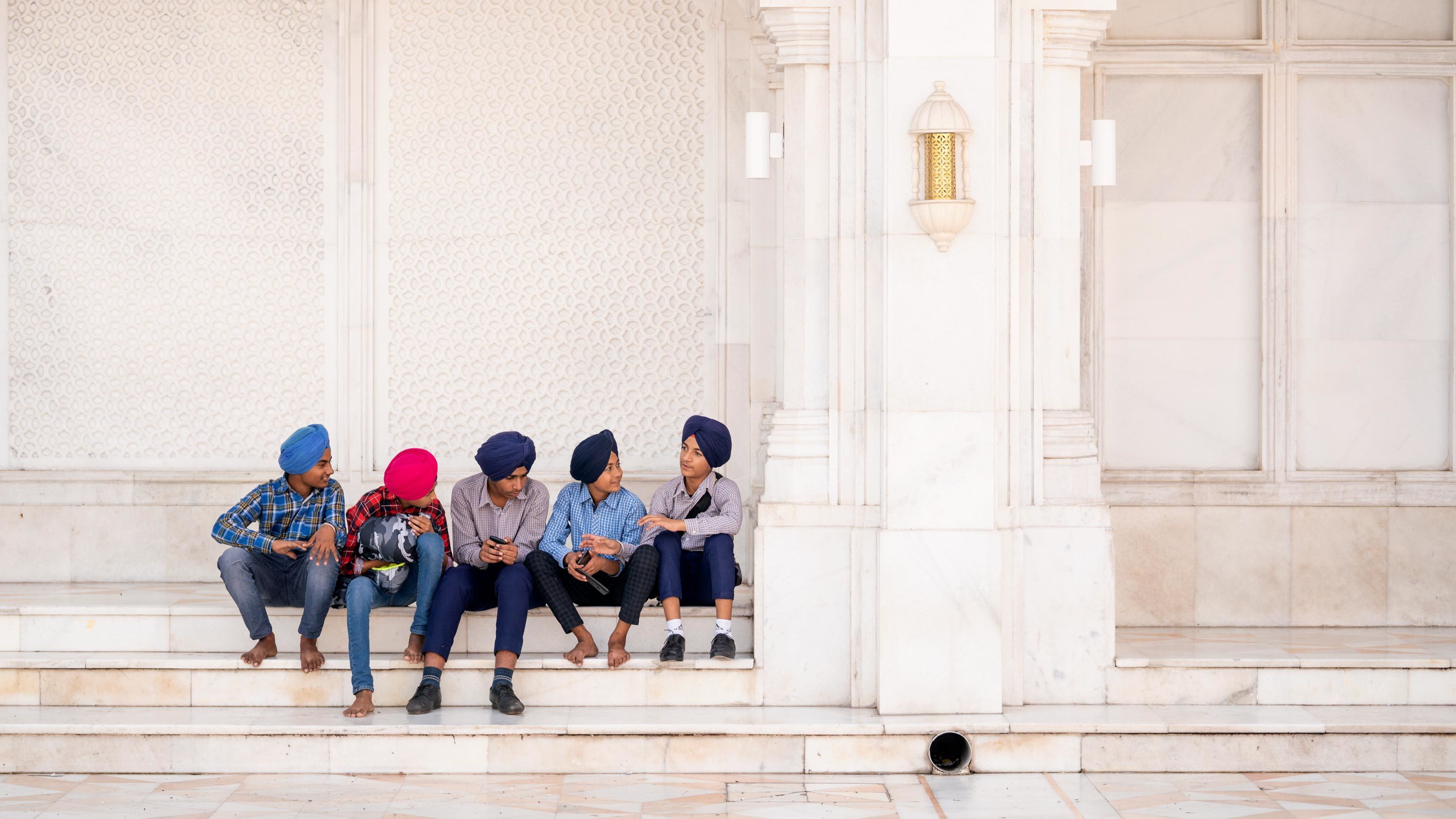 A group of boys in western clothes and turbans in a row on white marble steps