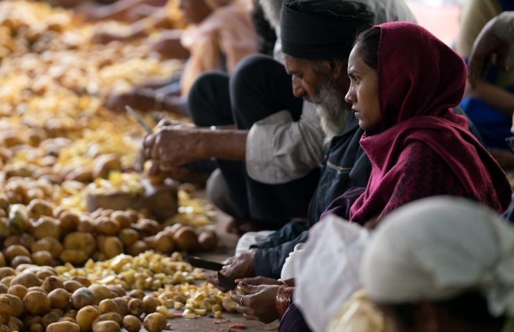 A group of people chop potatoes while sitting on the ground